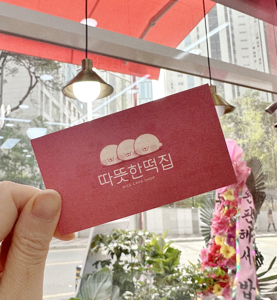 따뜻한 떡집 매장에서 촬영한 세 캐릭터가 그려진 분홍색 명함